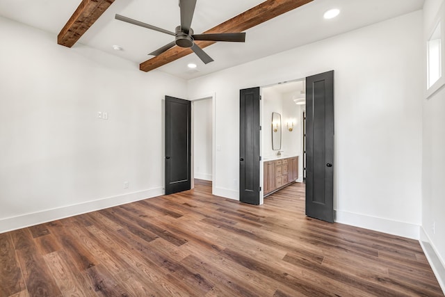 unfurnished bedroom featuring beam ceiling, ensuite bath, dark hardwood / wood-style floors, and ceiling fan