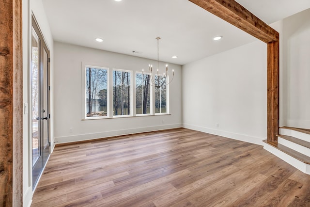 unfurnished dining area with an inviting chandelier and light hardwood / wood-style floors