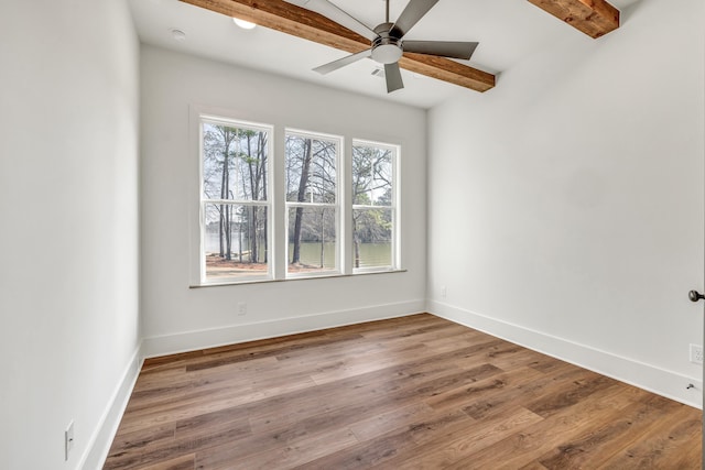 empty room with ceiling fan, beam ceiling, and light hardwood / wood-style flooring