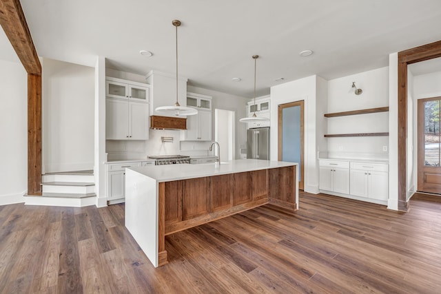 kitchen with a kitchen island with sink, dark wood-type flooring, high quality fridge, and white cabinets