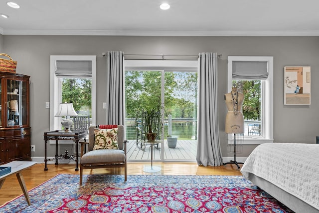 bedroom featuring access to exterior, wood finished floors, baseboards, and ornamental molding