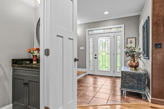 kitchen with tasteful backsplash, crown molding, baseboards, light wood-type flooring, and stainless steel appliances