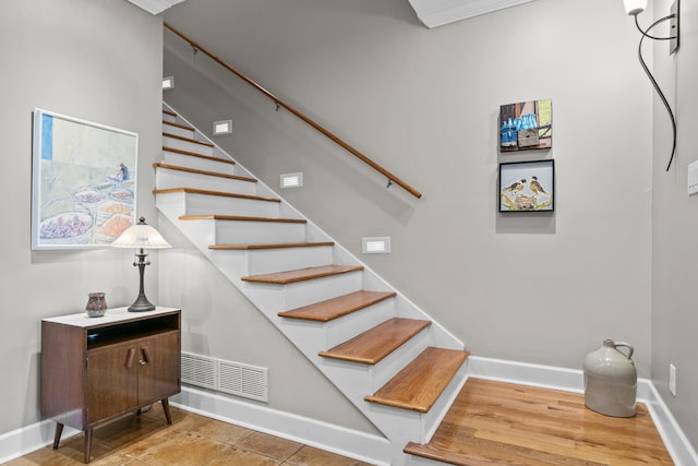 stairs with visible vents, baseboards, and wood finished floors