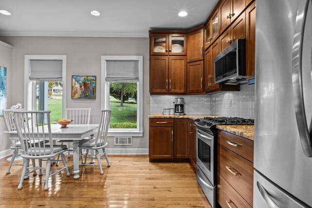 kitchen featuring stainless steel appliances, light stone countertops, ornamental molding, and decorative backsplash