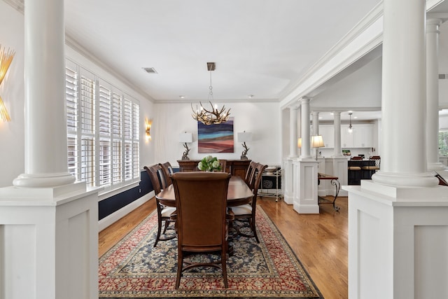 1191 Linger Longer Dr, Greensboro, GA 30642 - dining area featuring ornate columns, healthy amount of natural light, light wood-type flooring, and crown molding