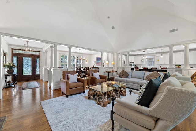 1191 Linger Longer Dr, Greensboro, GA 30642 - living area with a decorative wall, a chandelier, decorative columns, wood finished floors, and vaulted ceiling
