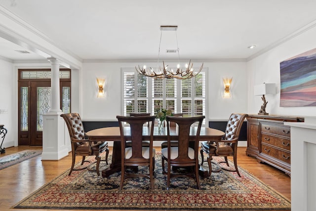 1191 Linger Longer Dr, Greensboro, GA 30642 - dining area featuring ornamental molding, a chandelier, light wood-type flooring, and decorative columns