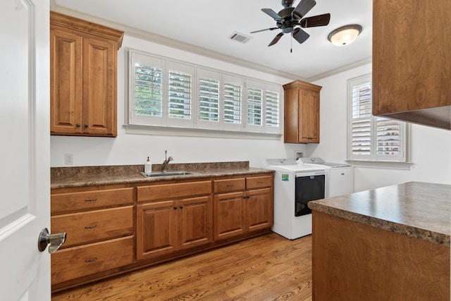 1191 Linger Longer Dr, Greensboro, GA 30642 - kitchen featuring dark countertops, washer and clothes dryer, brown cabinets, light wood-style flooring, and ornamental molding