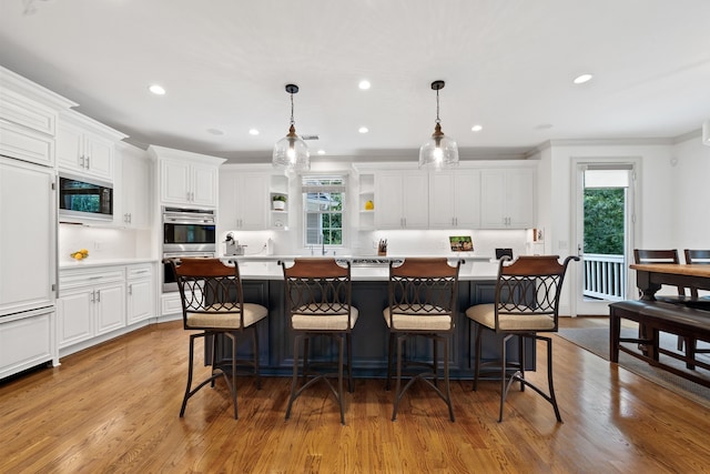 1191 Linger Longer Dr, Greensboro, GA 30642 - kitchen with built in microwave, wood finished floors, healthy amount of natural light, white cabinetry, and ornamental molding