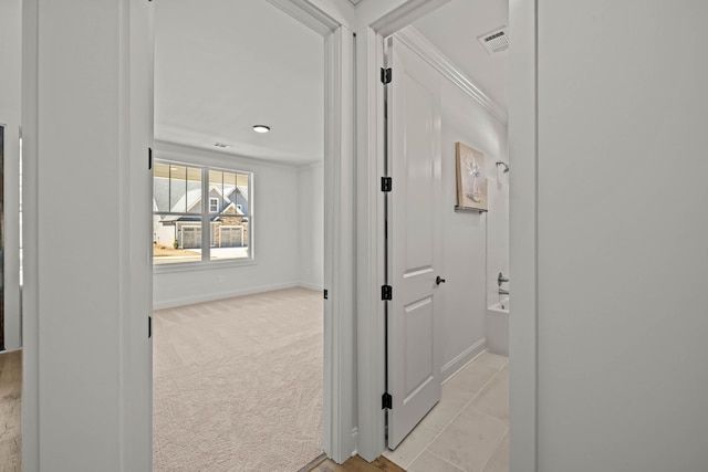 corridor featuring light colored carpet, visible vents, crown molding, and baseboards