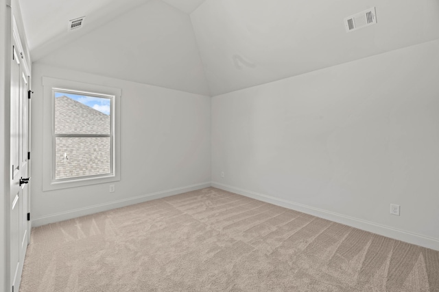 unfurnished room with visible vents, vaulted ceiling, light carpet, and baseboards