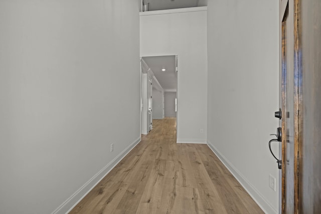 corridor with light wood-type flooring and baseboards