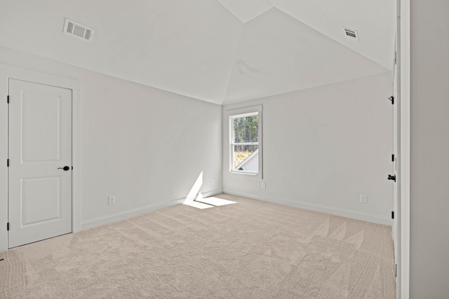 carpeted spare room featuring baseboards, visible vents, and vaulted ceiling