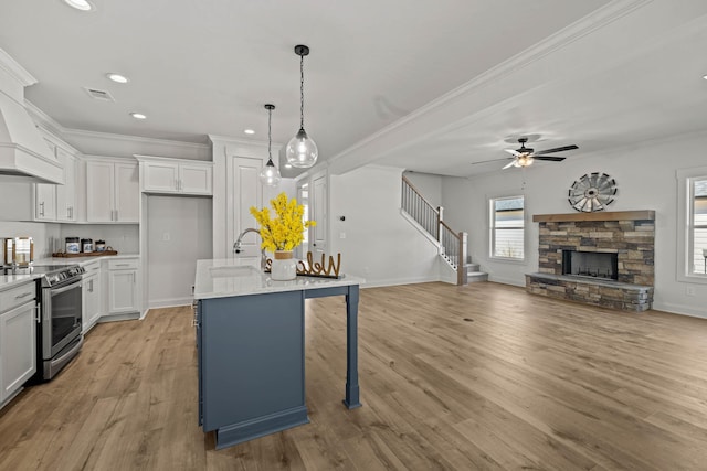 kitchen featuring a stone fireplace, a sink, visible vents, stainless steel range with electric cooktop, and open floor plan