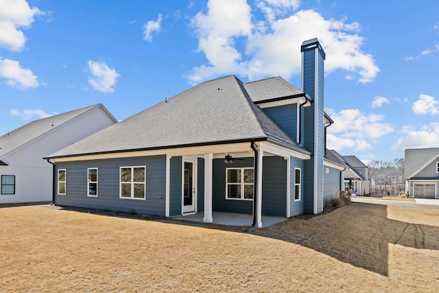 rear view of property featuring roof with shingles, ceiling fan, a chimney, and a patio