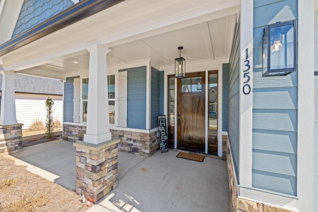 doorway to property with covered porch and stone siding