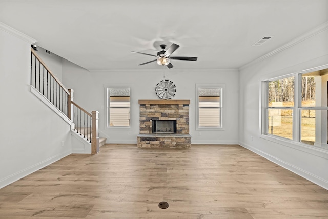 unfurnished living room featuring visible vents, stairway, wood finished floors, crown molding, and a stone fireplace