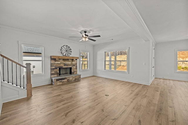 unfurnished living room featuring baseboards, light wood-style flooring, stairs, crown molding, and a fireplace