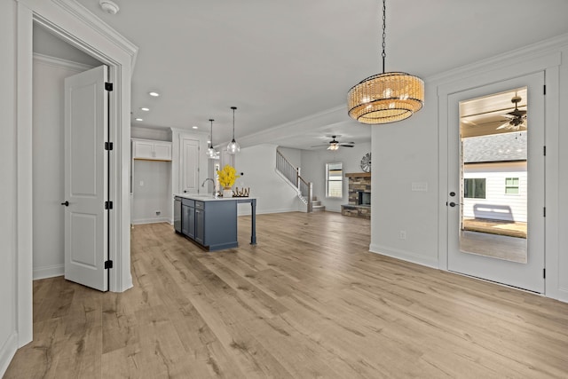 kitchen featuring ceiling fan, a fireplace, a sink, light wood-style floors, and open floor plan