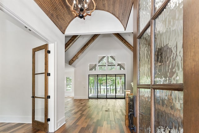 hall featuring beamed ceiling, wood-type flooring, a chandelier, and high vaulted ceiling