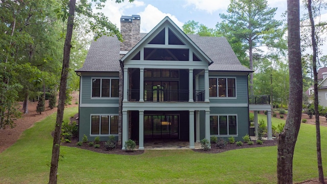 rear view of house featuring a balcony and a yard