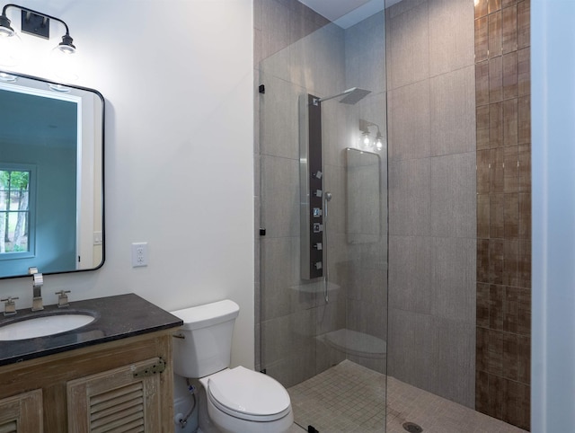 bathroom with vanity, tiled shower, and toilet