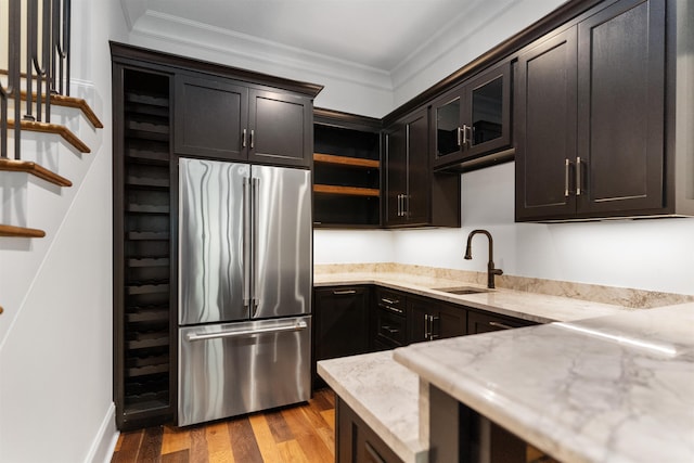 kitchen with stainless steel refrigerator, sink, ornamental molding, light hardwood / wood-style floors, and dark brown cabinets