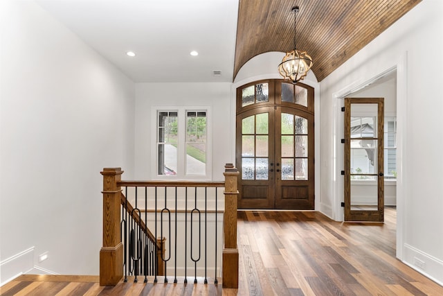 entrance foyer with french doors, lofted ceiling, an inviting chandelier, and hardwood / wood-style flooring