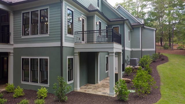 view of property exterior with a balcony, a yard, central AC, and a patio area