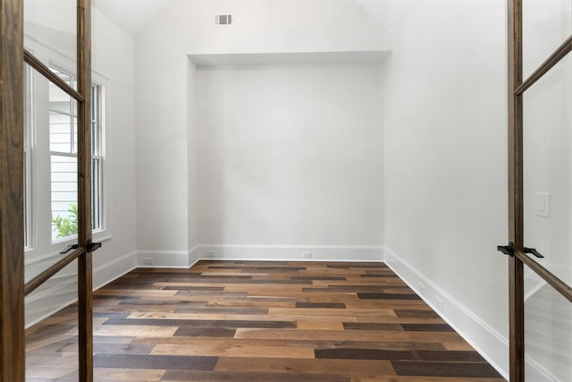 spare room featuring vaulted ceiling and dark hardwood / wood-style floors