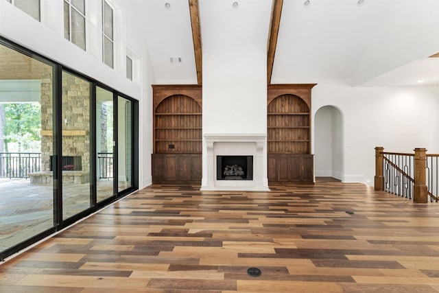 unfurnished living room with dark hardwood / wood-style flooring, a towering ceiling, and built in shelves