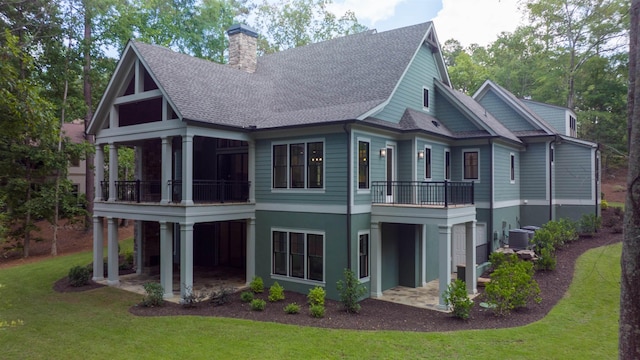 rear view of house with a balcony and a yard