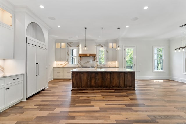 kitchen featuring a kitchen island with sink, decorative light fixtures, and white cabinets