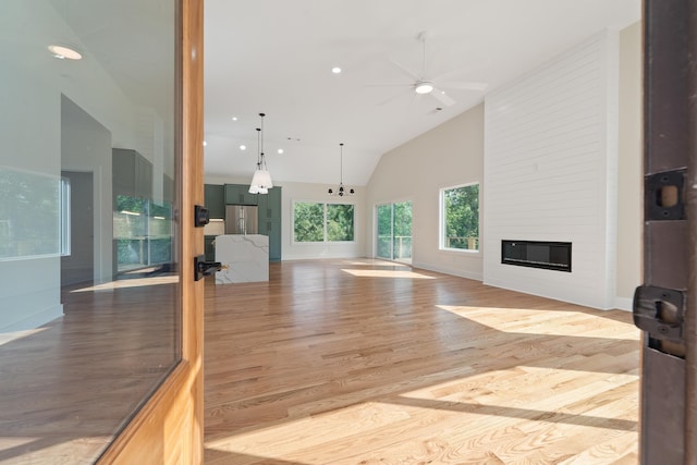 631 Susan Davis Rd, Sparta, GA 31087 - unfurnished living room with light wood finished floors, a ceiling fan, a fireplace, high vaulted ceiling, and baseboards