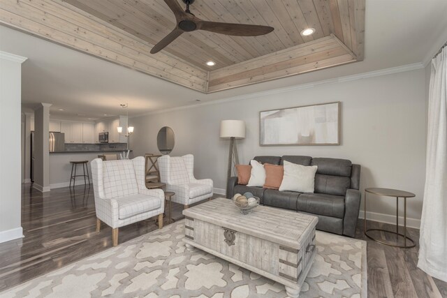 living room with a tray ceiling, wood-type flooring, ornamental molding, ceiling fan, and wood ceiling