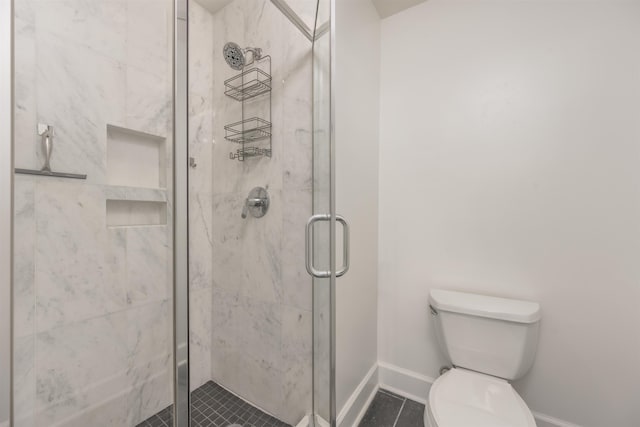 bathroom featuring toilet and a shower with shower door