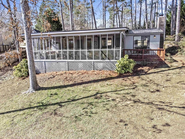 back of property with a sunroom and a lawn