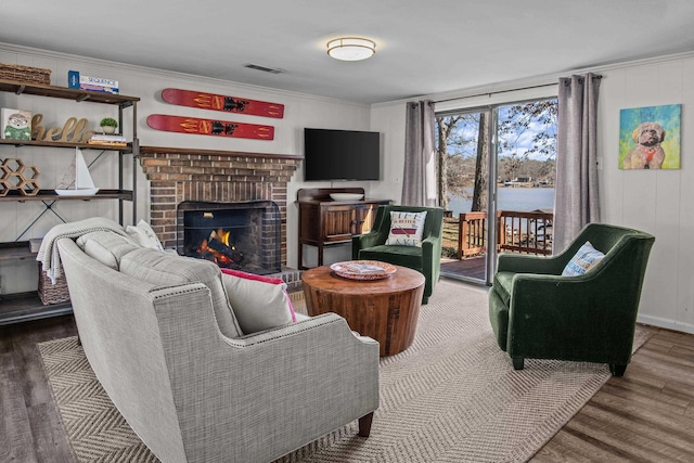 living room with hardwood / wood-style floors, ornamental molding, and a fireplace