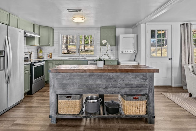 kitchen featuring green cabinetry, appliances with stainless steel finishes, sink, and stacked washer / dryer