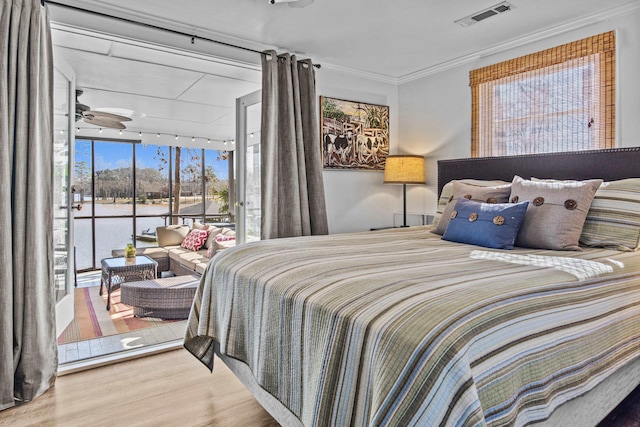 bedroom with hardwood / wood-style flooring, a water view, access to outside, a wall of windows, and ornamental molding