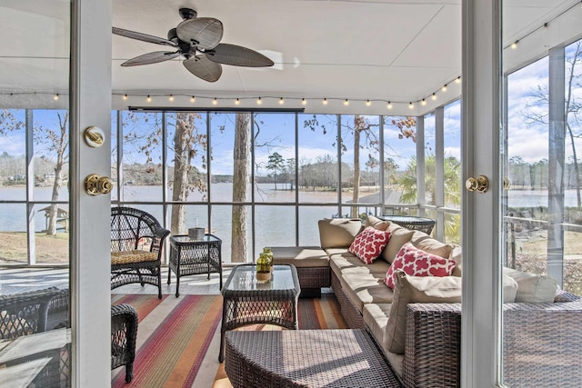 sunroom / solarium with a water view, rail lighting, and ceiling fan