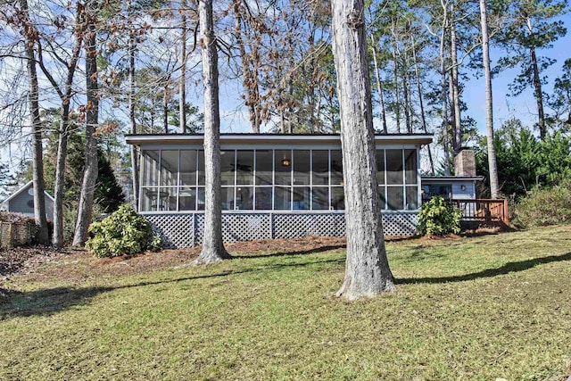 back of property with a sunroom and a lawn