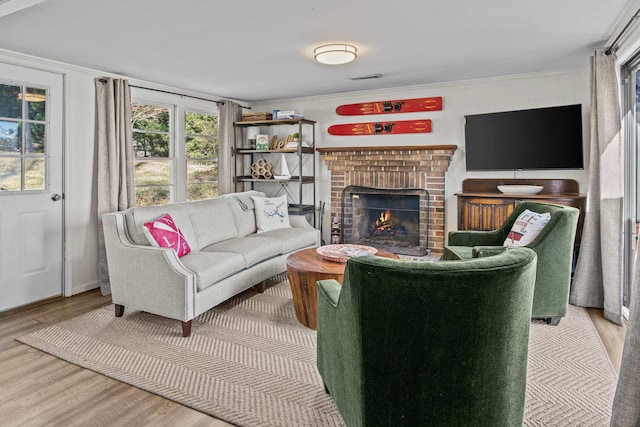 living room with hardwood / wood-style floors, crown molding, and a brick fireplace