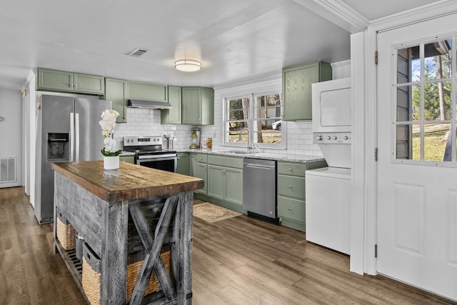 kitchen with green cabinetry, stainless steel appliances, sink, stacked washer and clothes dryer, and dark hardwood / wood-style floors