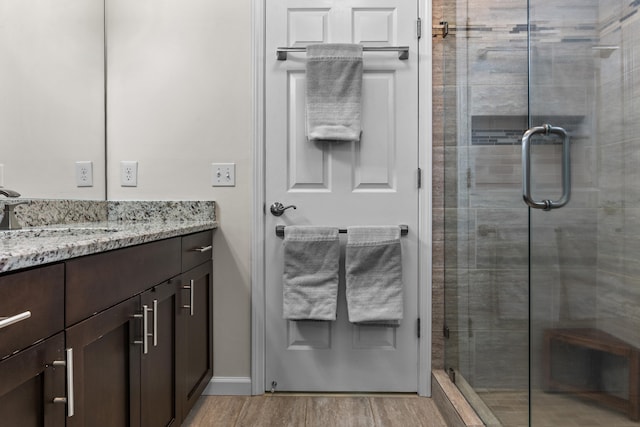 full bath with wood finished floors, vanity, and a shower stall