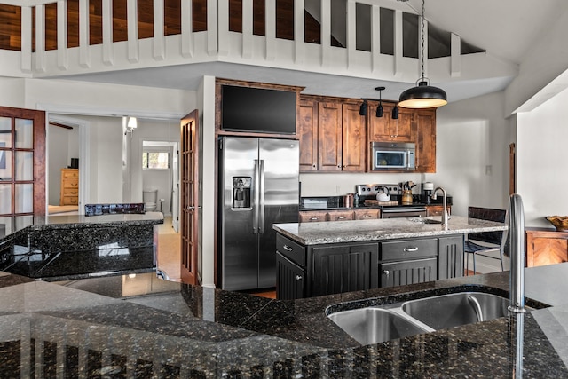 kitchen featuring stainless steel appliances, decorative light fixtures, a kitchen island, and dark stone countertops