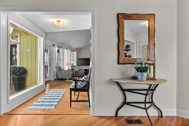 interior space with lofted ceiling, visible vents, baseboards, and wood finished floors