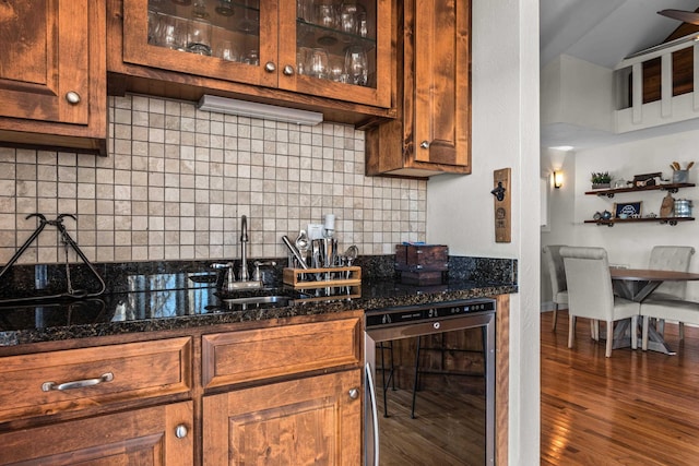 kitchen featuring decorative backsplash, glass insert cabinets, dark stone counters, and dark wood-type flooring