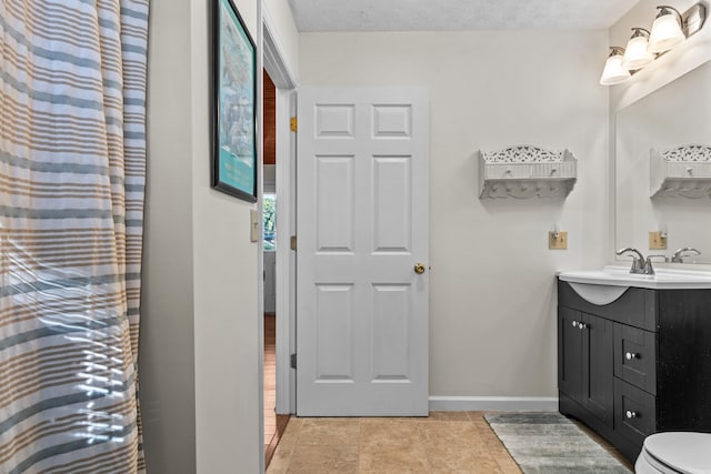 bathroom featuring tile patterned flooring, baseboards, a textured ceiling, and vanity