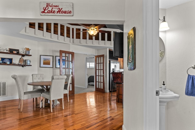 dining room with a ceiling fan, visible vents, baseboards, and wood finished floors